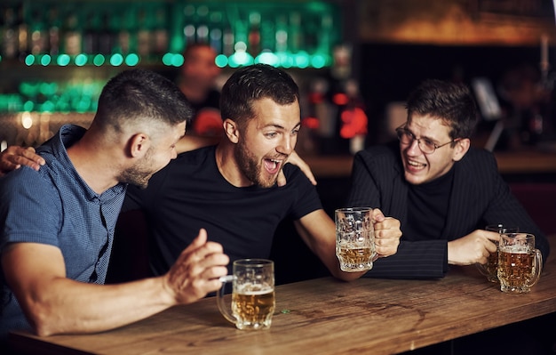 Drie vrienden rusten in de kroeg met bier in handen