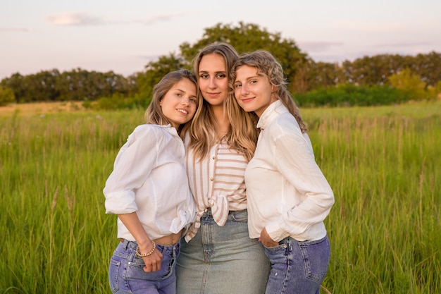 Foto drie vrienden rusten uit in de natuur. ze glimlachen en maken foto's