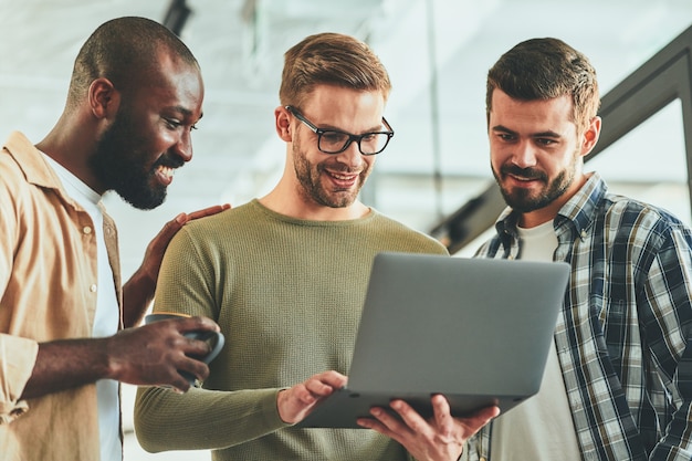 Drie vrolijke jongens kijken naar iets op het scherm van de laptop