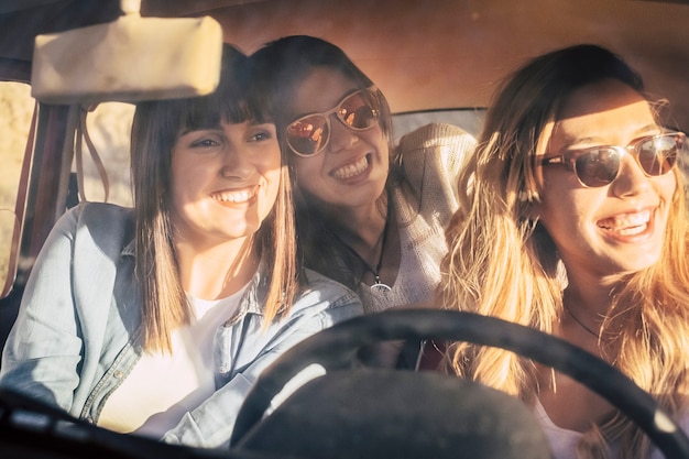 Foto drie vrolijke vrouwelijke vrienden die in auto reizen. vriendinnen die plezier hebben terwijl ze genieten van een autorit op een heldere zomerdag van vakantie. vriendinnen bewonderen iets interessants vanuit de auto