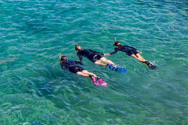 Drie vrouwelijke duikers met duikmaskers en flippers duiken in kristalhelder water in Eilat Rode Zee Israël Duikers trainen aan zee Jonge meisjesduiker in zwarte duikpakken die in water spelen