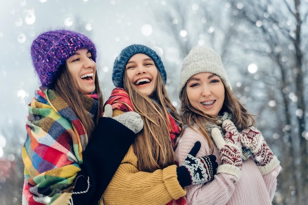 Foto drie vrouwelijke vrienden buiten in gebreide hoeden die plezier hebben op een sneeuwige koude weergroep van jonge vrouwtjes