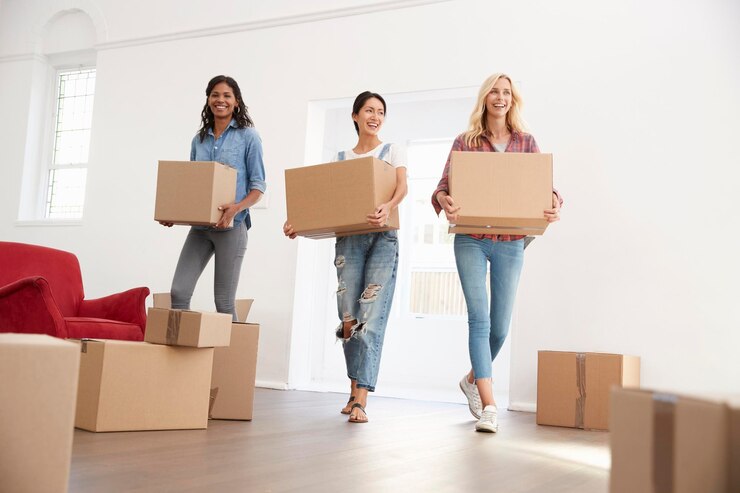 Foto drie vrouwelijke vrienden dragen dozen naar hun nieuwe huis op de dag van de verhuizing