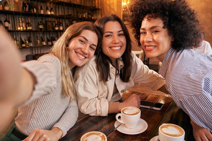 Foto drie vrouwelijke vrienden nemen een selfie terwijl ze plezier hebben in de cafeteria gelukkige glimlachende meisjes die naar de camera kijken