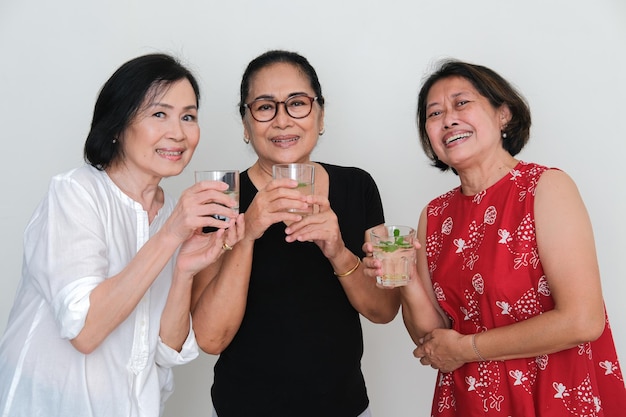 Drie vrouwen die glazen drank vasthouden, verzamelen zich op een reüniefeest