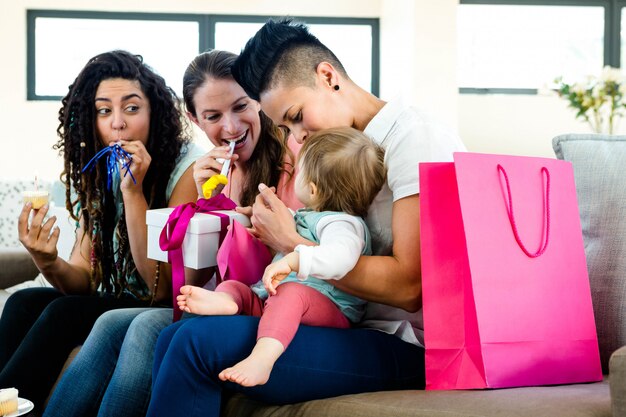 Drie vrouwen die op een laag zitten die de eerste verjaardag van een baby viert