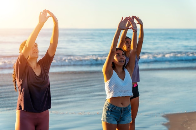 Drie vrouwen die samen yoga doen of oefeningen doen op het strand