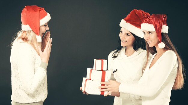 Drie vrouwen in kostuum van de kerstman met kerstinkopen