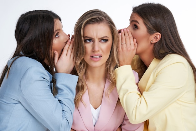 Drie vrouwen in pastelkleurige pakken poseren op een witte achtergrond