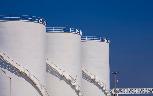 Drie witte brandstoftanks met oliepijpleidingsysteem op aardolie-industriegebied in de haven