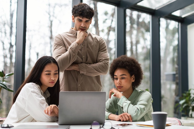 Drie zakelijke collega's werken samen en kijken naar laptop op kantoor