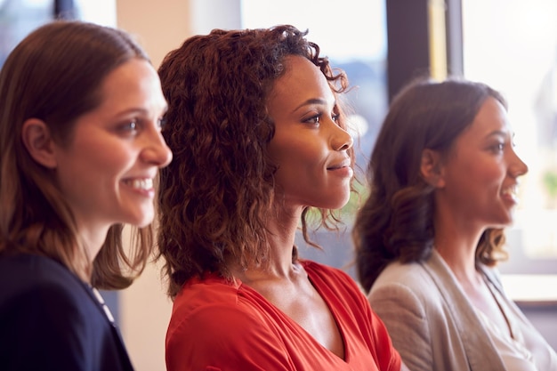 Drie zakenvrouwen staan samen in een modern open kantoor