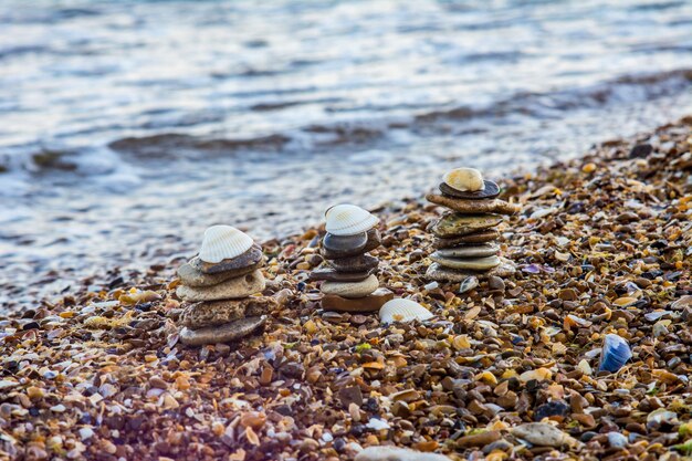 Drie zeekiezeltorentje en witte schelp bovenop. zee stenen op het strand. zomervakantie seizoen bij badplaatsen afbeelding.