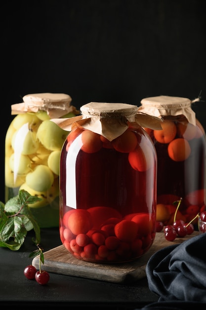 Drie zelfgemaakte kersen- en appelcompote in grote glazen potten.