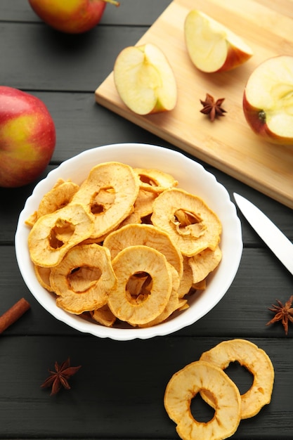 Dried apple chips with cinnamon and star anise with fresh apple Homemade dried organic apple sliced on black background Vertical photo