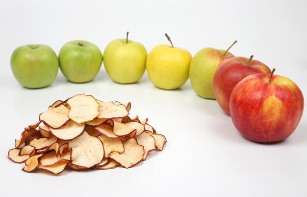 Dried Apple slices surrounded by fresh apples on white background