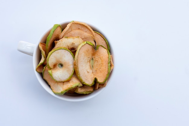 Dried apple slices in white cup on white