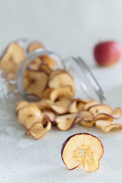 Dried apples chips in glass jar on light wood