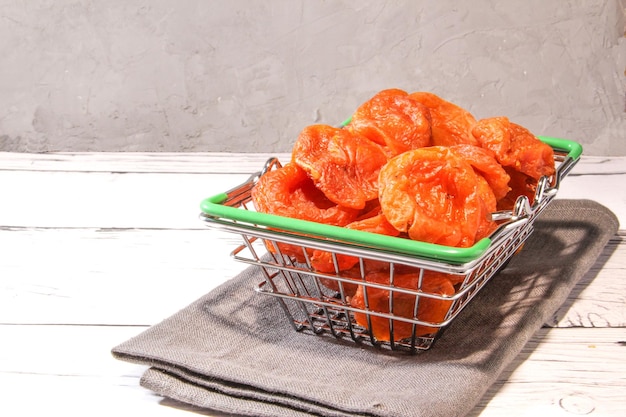 Dried apricot in the basket on the wooden background Sweet raw orange dried apricot in the plate