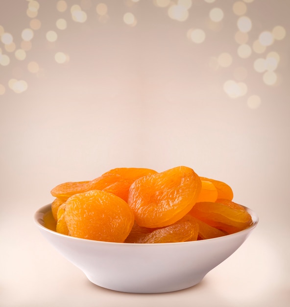 Dried apricot into a bowl on beige background.