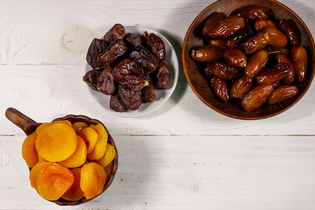 Dried apricots and dates fruit on white wooden table Top view