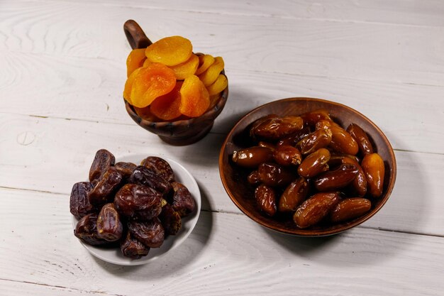 Dried apricots and dates fruit on white wooden table