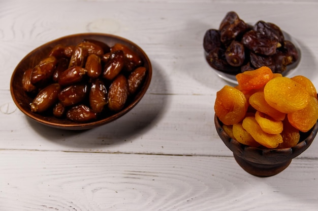 Dried apricots and dates fruit on white wooden table