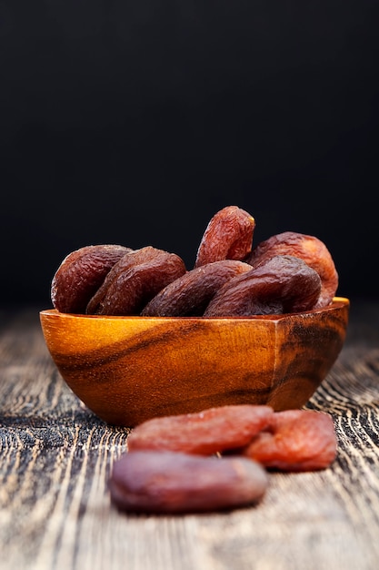 Dried apricots made from natural apricots, dried apricots of dark color, natural drying without the use of acceleration and non-natural chemical elements, dry fruits on a wooden table