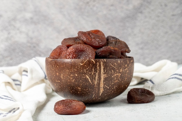 Photo dried apricots on stone background dark dried apricots in a glass bowl diet foods close up
