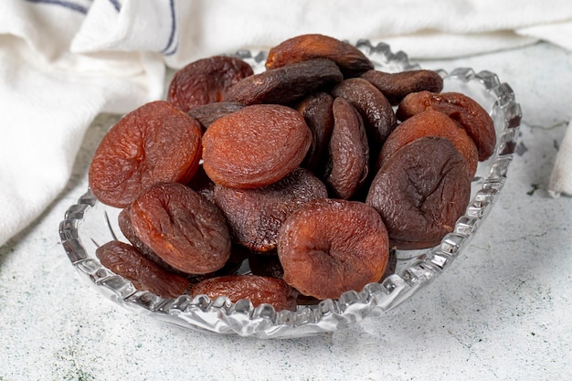 Photo dried apricots on stone background dark dried apricots in a glass bowl diet foods close up