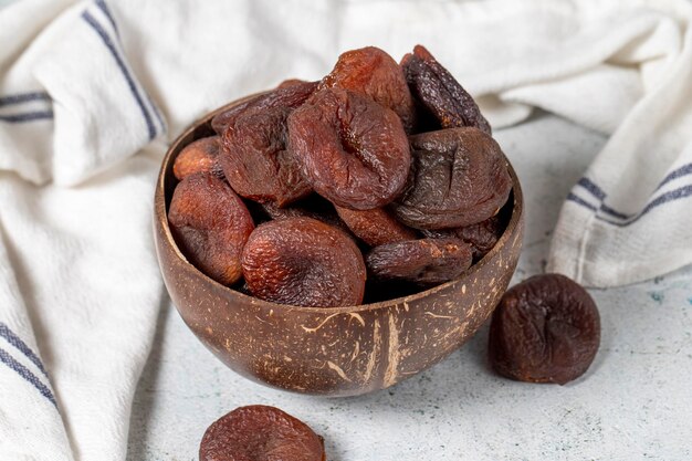 Photo dried apricots on stone background dark dried apricots in a glass bowl diet foods close up