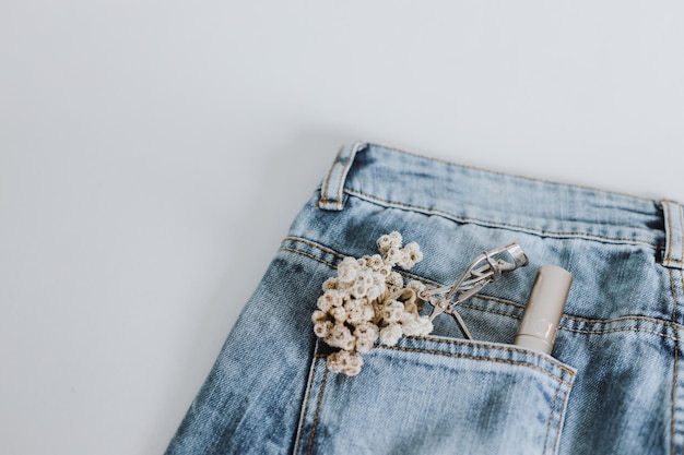 Dried baby breath flower lashes curler and mascara on jeans pocket Make up artist and cosmetic pr