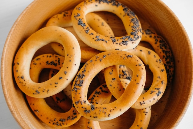 Dried bagels with poppy seeds in a wooden bowl on a white background