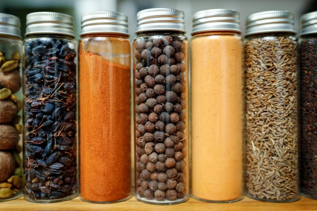 Dried barberry ginger and cumin or zira and other spices in transparent jars among other spices on the table in home kitchen