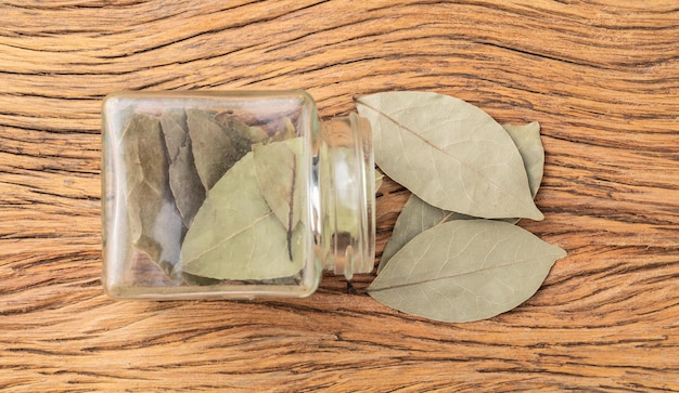 Dried bay leaves on a glass pot over wooden table