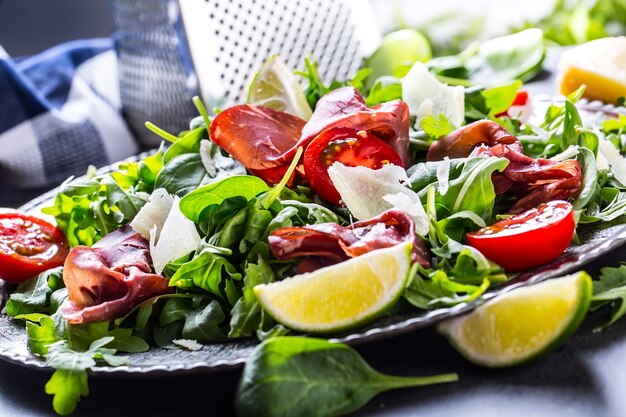 Dried beef bresaola. Salad bresaola arugula baby spinach tomatoes lime and cheese parmesan.