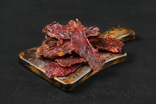 Dried beef jerky slices on wooden board