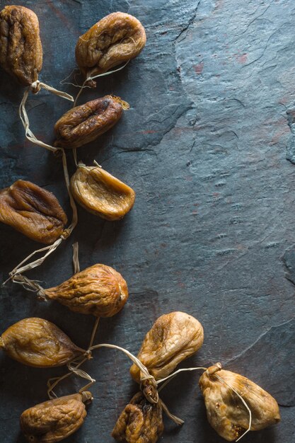 Dried beige figs with rope on a gray stone on the left free space