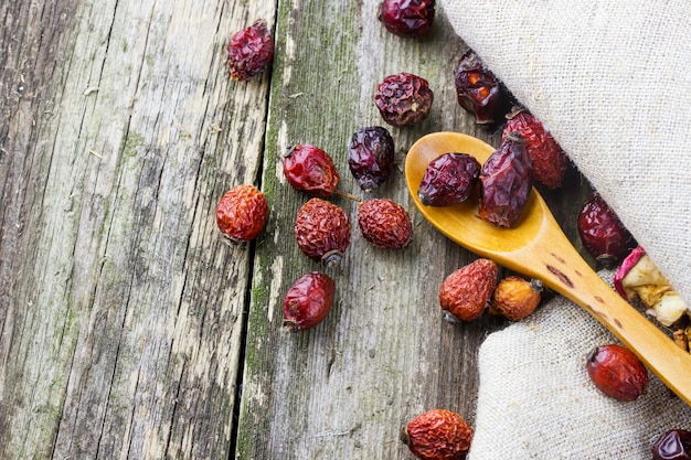 Dried berries in a wooden spoon on an old wooden table