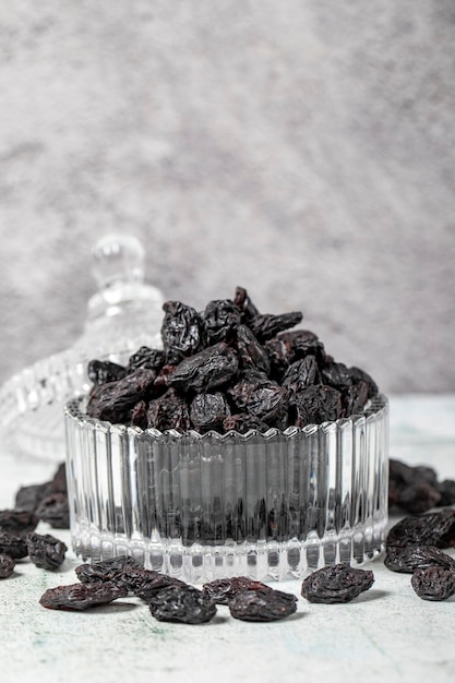 Dried black grapes on stone background Dried grapes in glass bowl Nuts varieties Healthy eating close up