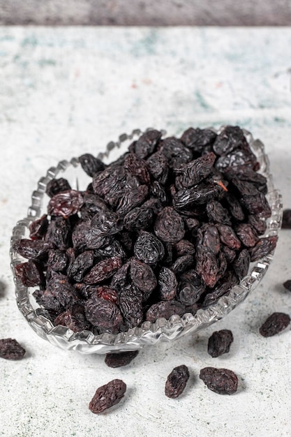 Dried black grapes on stone background Dried grapes in glass bowl Nuts varieties Healthy eating close up