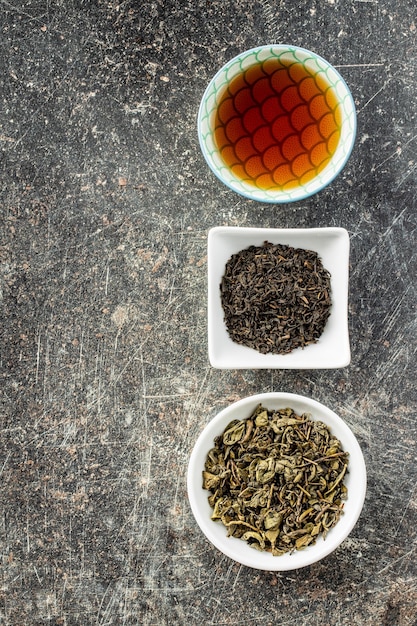 Dried black and green tea leaves in bowl Top view