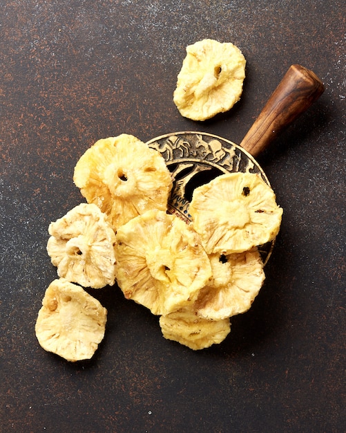 Photo dried candied pineapple rings. sliced sweet fruits on brown concrete background. top view.