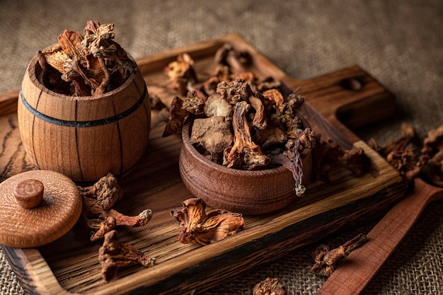 Dried chanterelle mushrooms (CantharÃÂllus cibÃÂrius), on a wooden board, on a rough woven surface, burlap