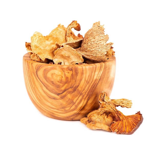 Dried chanterelle mushrooms in olive bowl, isolated on white background. Dried forest chanterelle mushrooms. Cantharellus cibarius.