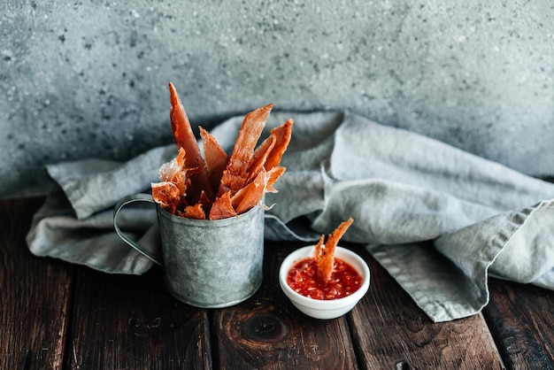 Dried chicken dried poultry cut into strips in a metal bucket\
on a wooden background serving a meal in a restaurant high quality\
photo