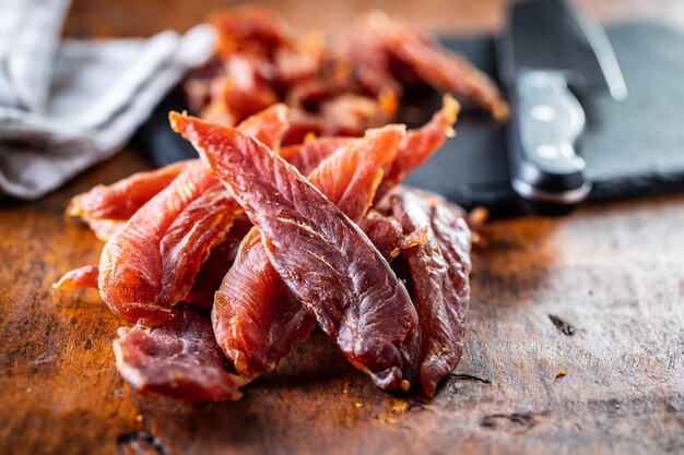 Foto carne di pollo essiccata gustosa carne a scatti su tavolo di legno