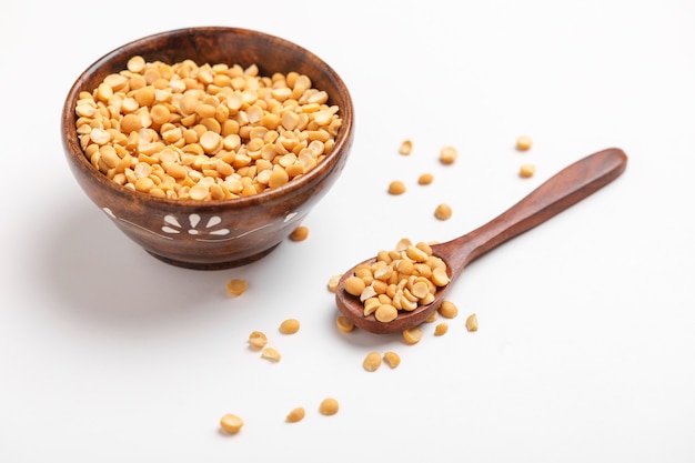 Dried chickpea lentils in wooden bowl and spoon on white background , Split Chickpea Also Know as Chana Dal