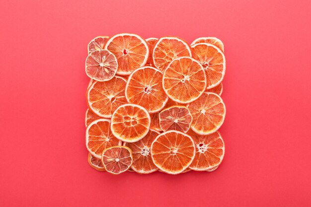 Сушеные цитрусовые ломтики лимонов и апельсинов на кораллово-розовом.