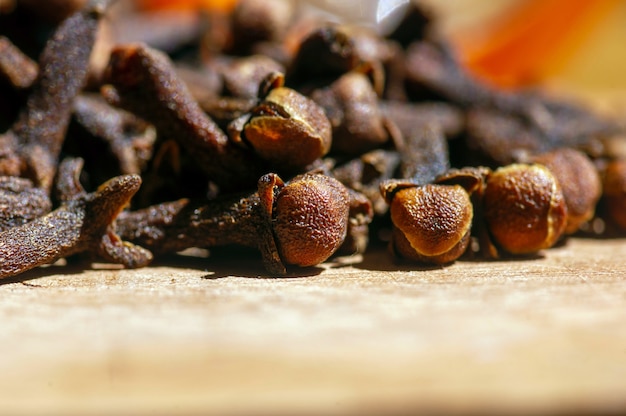 Dried clove seeds, in shallow focus, on the wooden table.